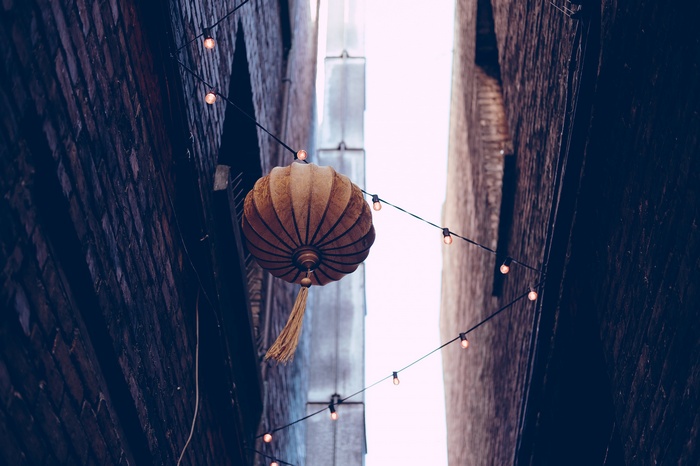 Lantern hanging in a narrow urban alley with string lights