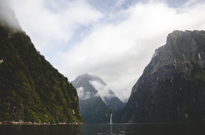 Waterfall cascading down mountains into a dark lake