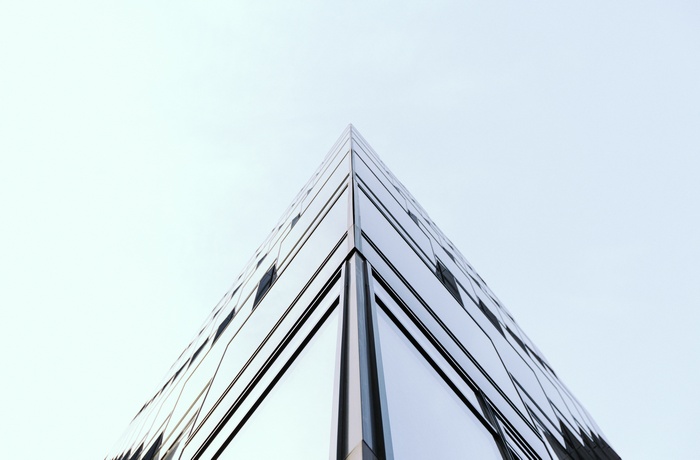 Modern glass building corner looking up at sky