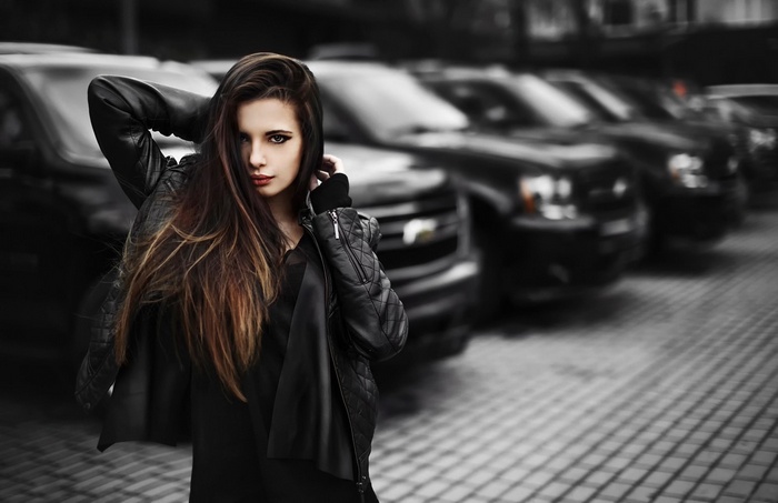 Woman in leather jacket with long hair and black cars