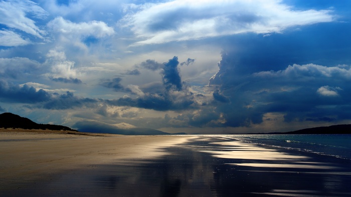 Beach with dramatic clouds and reflections