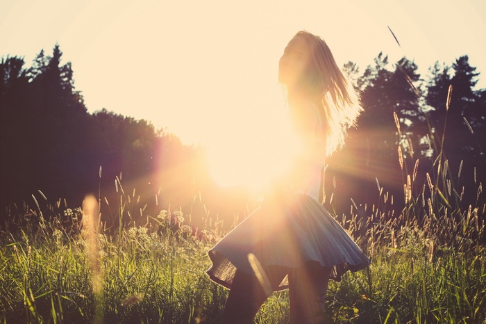 Woman with blonde hair in a field at sunset
