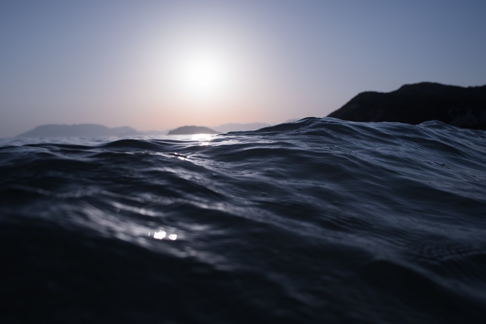 Ocean waves at sunset with islands in the background