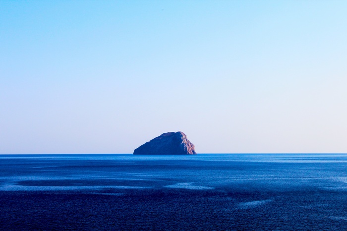 Island in the vast blue sea under a clear sky