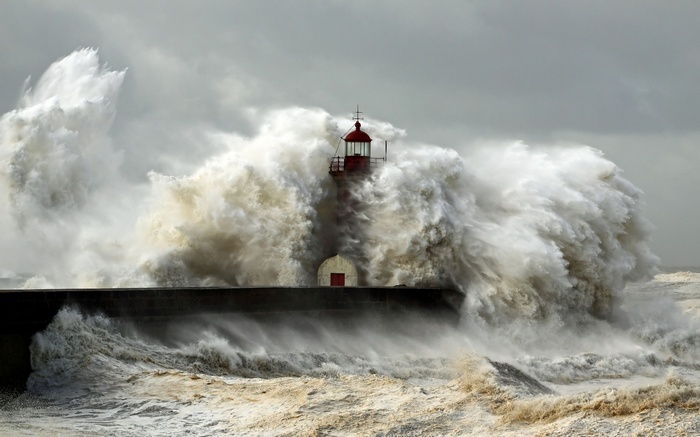 Lighthouse battered by massive waves during a storm
