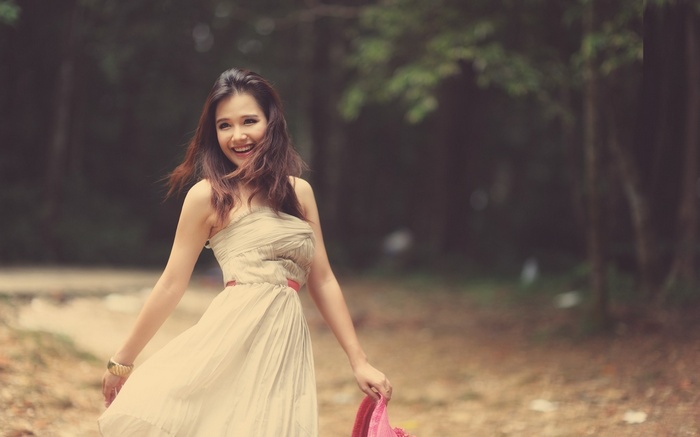 Asian woman in a dress smiling in a forest