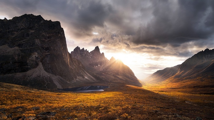 Sun rays over a valley with mountains and dry grass