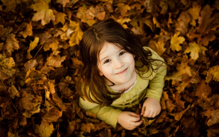 Young girl smiling in fallen autumn leaves