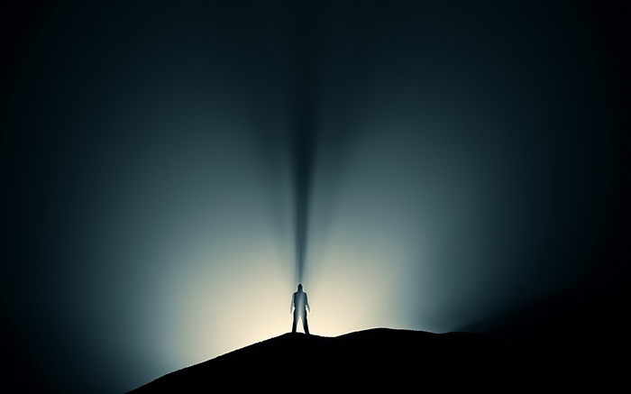 Silhouette of a man on a hill with light rays