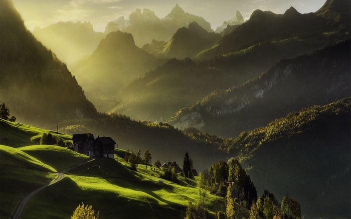 Sun rays over houses in a mountain landscape