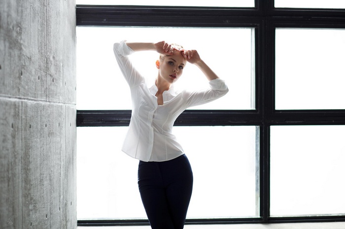 Woman in white blouse and black pants by window