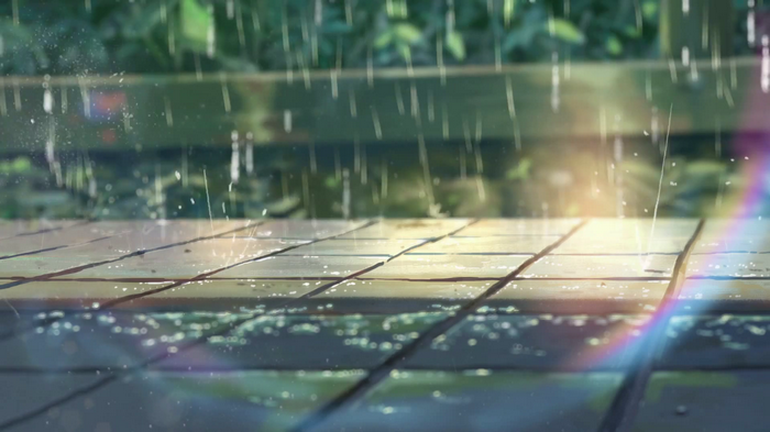 Rain falling on a wooden walkway with a rainbow lens flare