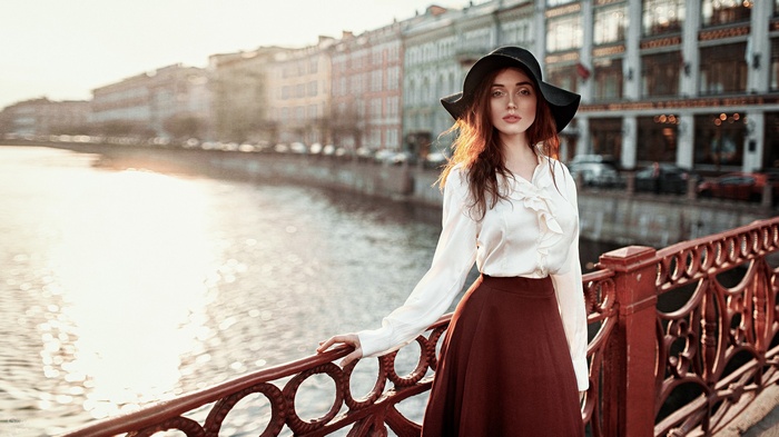 Woman in a hat and white blouse by a river