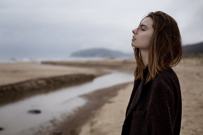 Woman with long hair on a beach with a stream