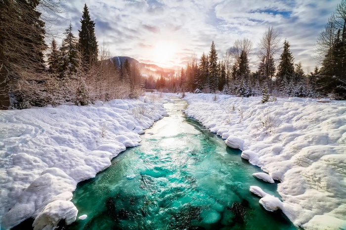Turquoise river flowing through a snowy forest landscape