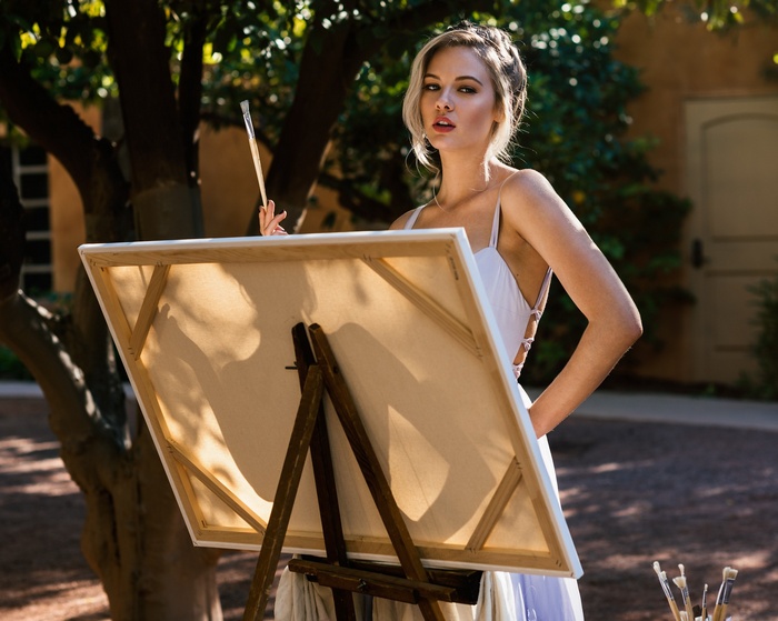 Blonde woman painting outdoors on an easel