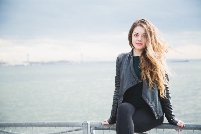 Woman in leather jacket sitting by the water
