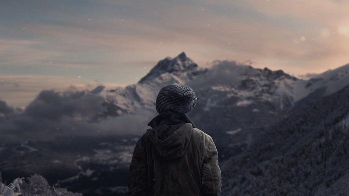 Person in beanie looking at snowy mountains