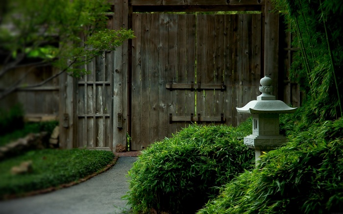 Wooden gate in a Japanese garden with a stone lantern