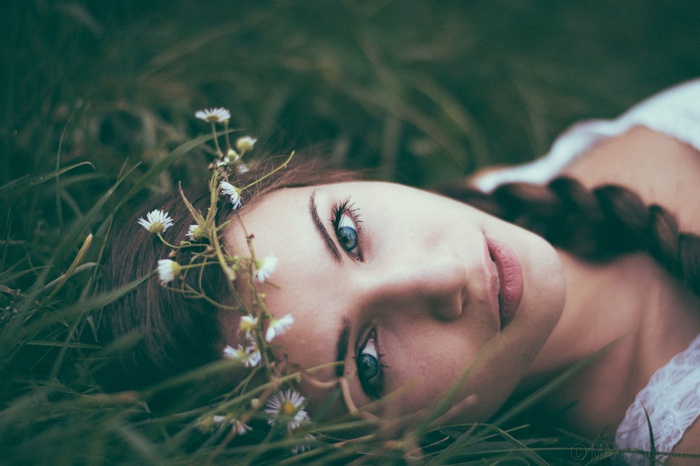Woman with flowers in her hair lying in grass