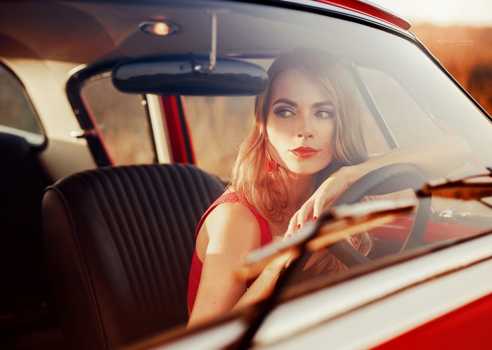 Woman in red dress in a vintage car