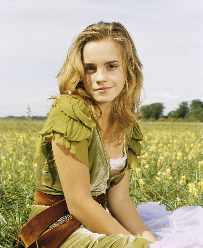 Emma Watson sitting in a field of yellow flowers