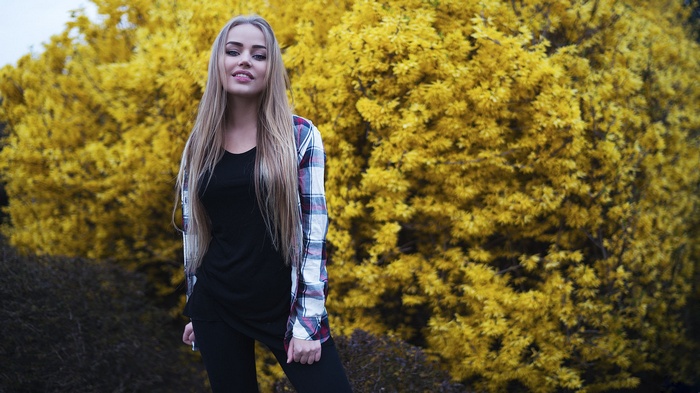 Maria Puchnina posing in front of a yellow bush