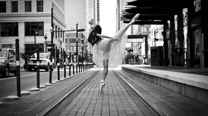 Ballerina dancing on city street with tram tracks