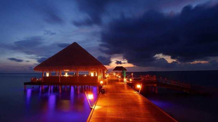 Overwater restaurant with thatched roof at dusk
