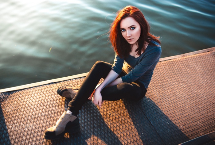 Redhead woman with blue eyes sitting by the water