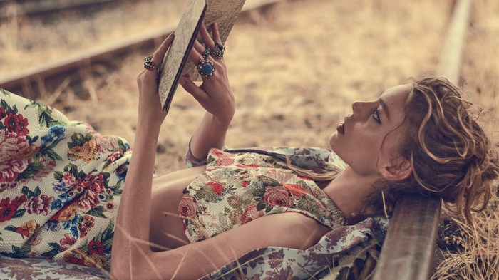 Woman reading a book on railway tracks