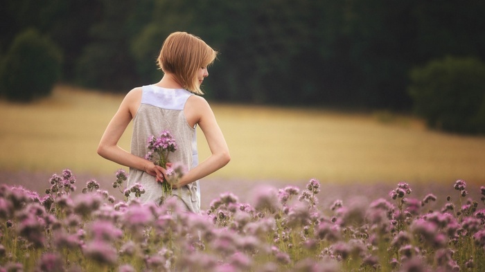 Woman holding flowers in a field of purple flowers