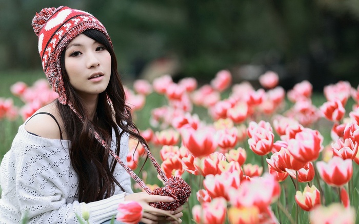 Asian woman wearing a beanie in a field of tulips