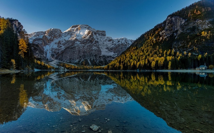 Snow-capped mountains reflected in a calm lake in the Alps