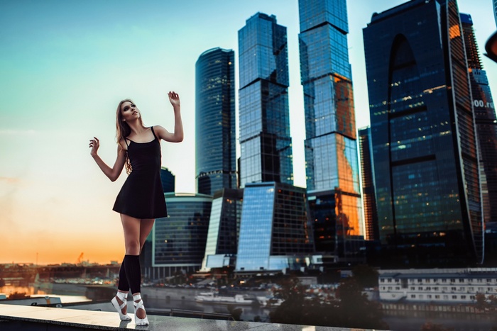 Ballerina posing in front of Moscow skyscrapers at sunset
