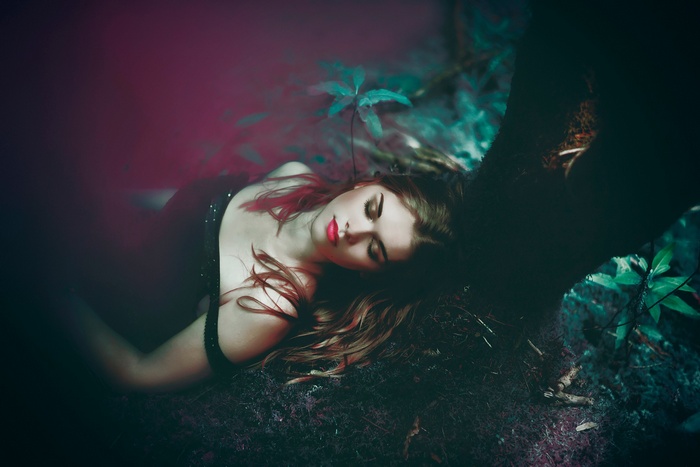 Woman lying down in a dark forest