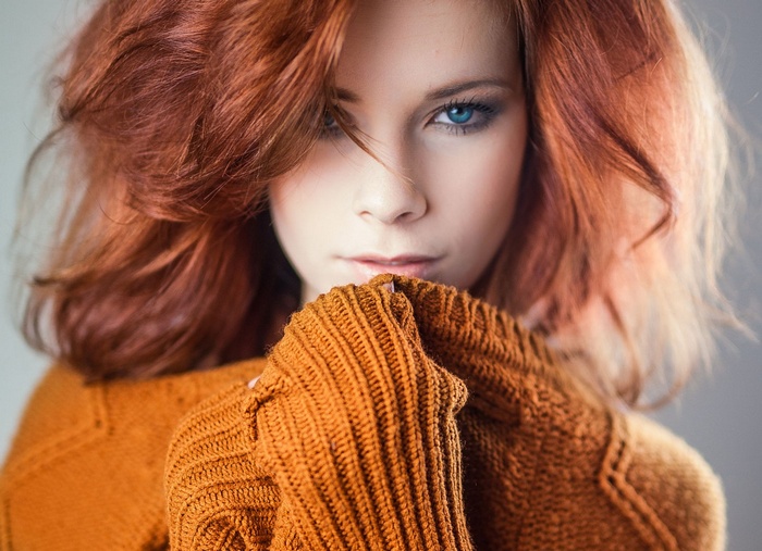 Redhead woman with blue eyes wearing an orange sweater