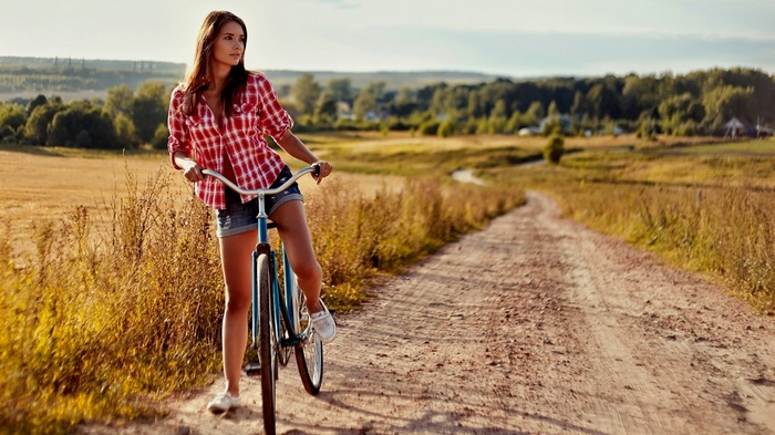 Woman with a bicycle on a dirt road