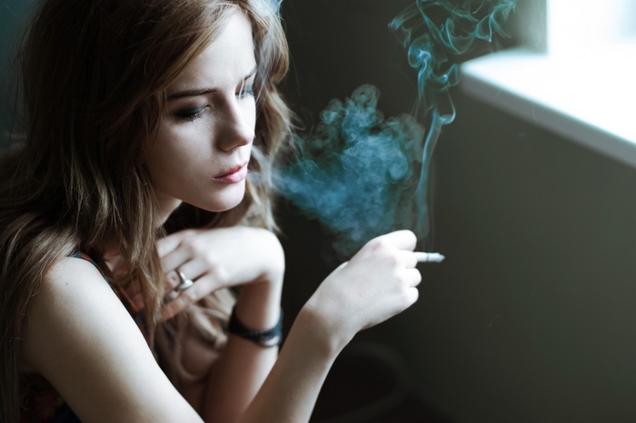 Woman smoking a cigarette with smoke rising