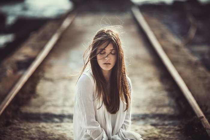 Woman with freckles sitting on railway tracks