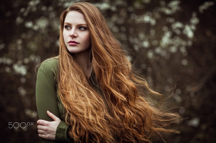 Redhead woman with long wavy hair looking away