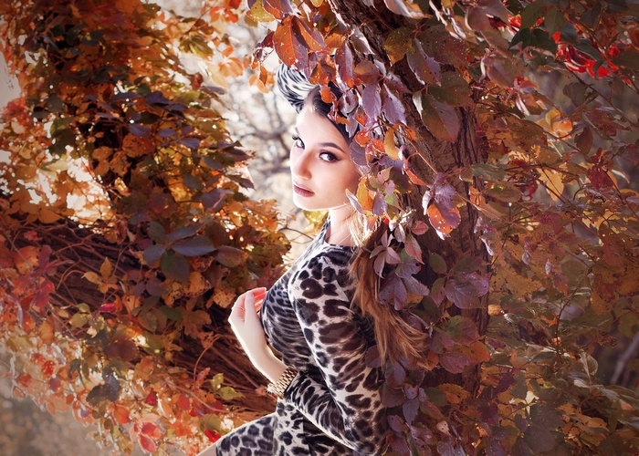 Woman in leopard print dress among autumn leaves