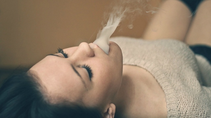 Woman lying on back exhaling smoke
