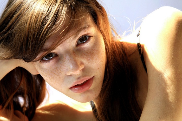 Brunette woman with freckles looking at viewer