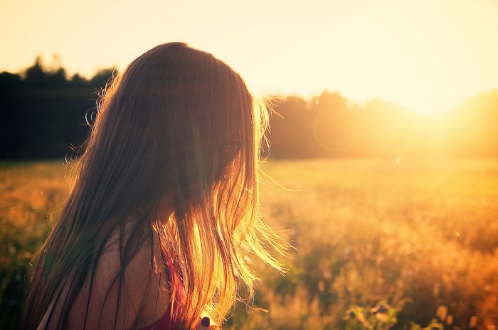 Woman with long hair in a field at sunset