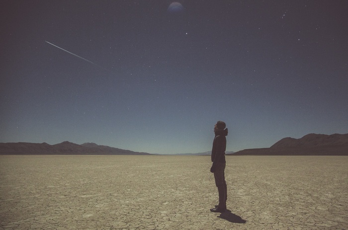 Man looking at a meteor shower in a desert