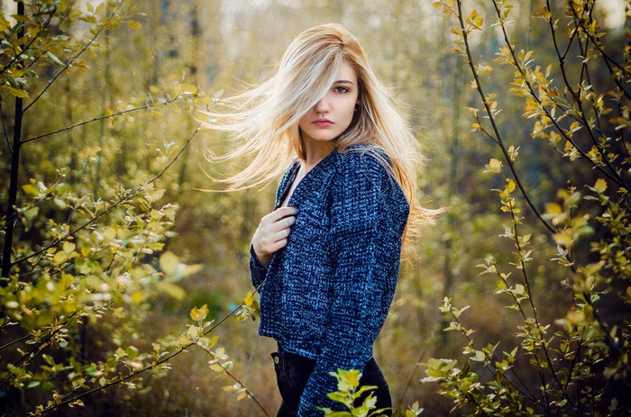 Woman with blonde hair in a blue sweater outdoors
