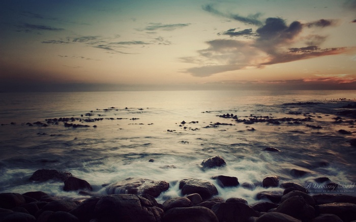 Ocean waves crashing on rocks at sunset