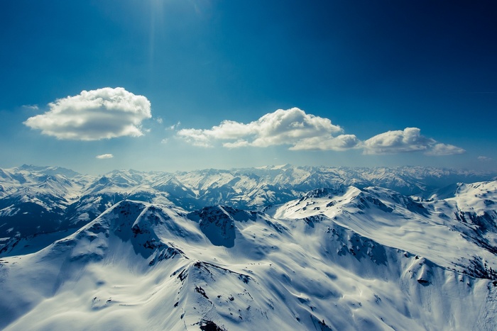 Snowy mountains under a blue sky with clouds