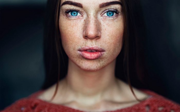 Woman with blue eyes and freckles looking at viewer
